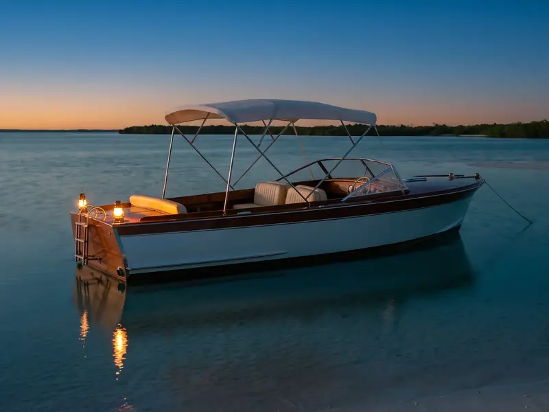 The same boat at blue hour, with two small lanterns glowing on the stern.