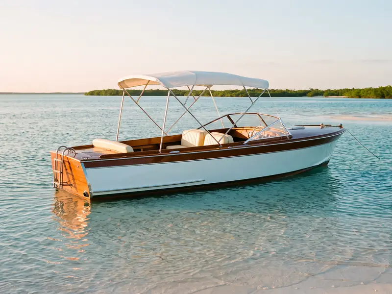 A classic wooden day boat at anchor on a sandbar at golden hour.