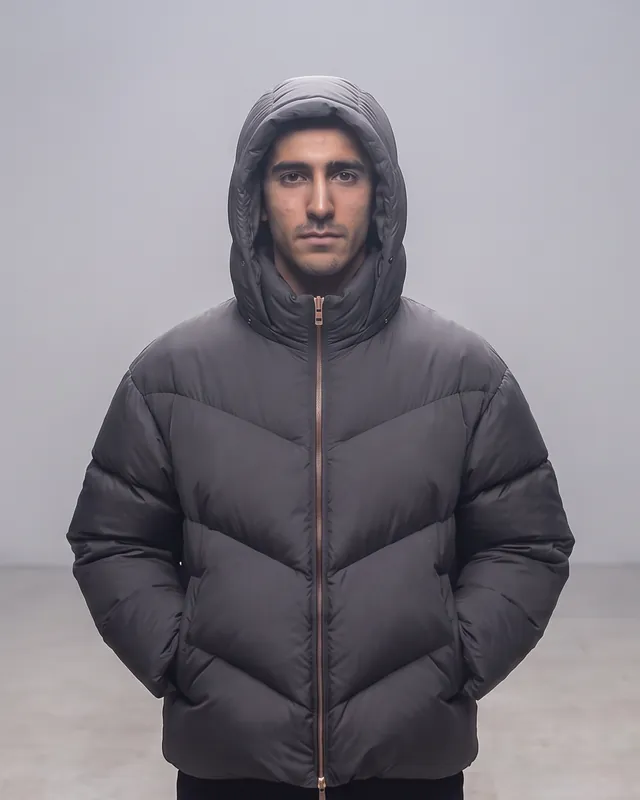 The one who stays: a dark-haired man, hood up, in the graphite FIRN jacket, alone in the haze. AI-generated.