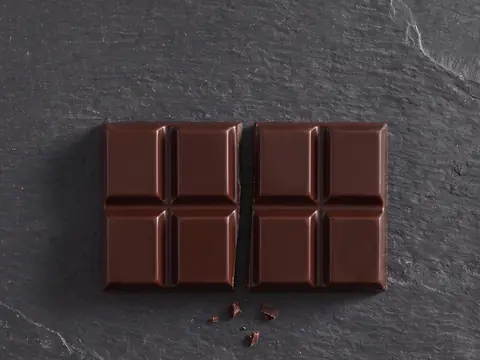 The same bar snapped between the fourth and fifth squares, three crumbs at the break