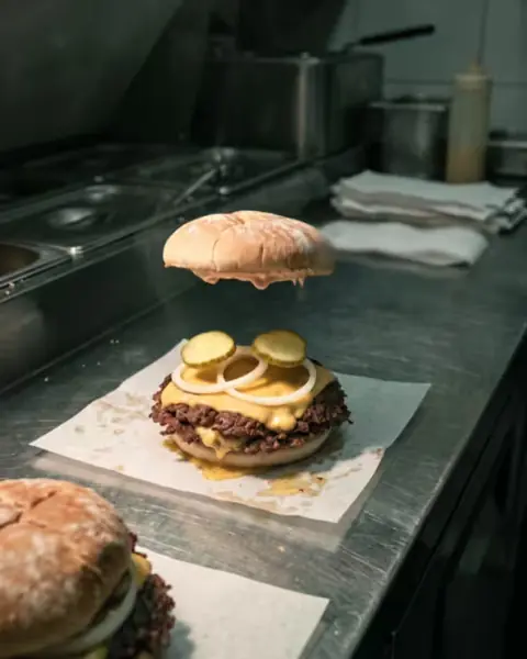 Film frame 40: the hand has gone and the top bun lifts away.