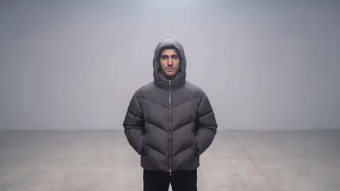 The same man stands alone in the empty grey haze, hands in his pockets, looking into the camera.