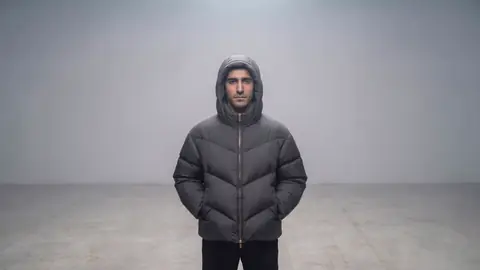 The last frame: the man stands alone in the grey haze, hands in his pockets.